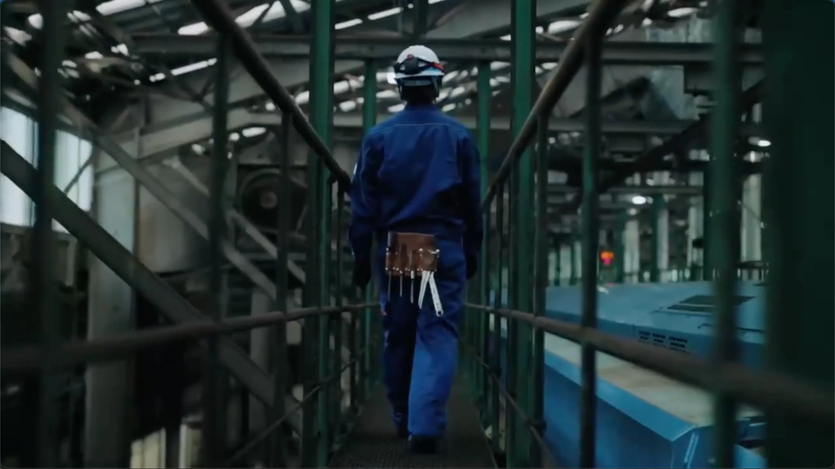 Odakyu industrial worker in a hard hat walking down a metal walkway, featured on the Claris homepage.